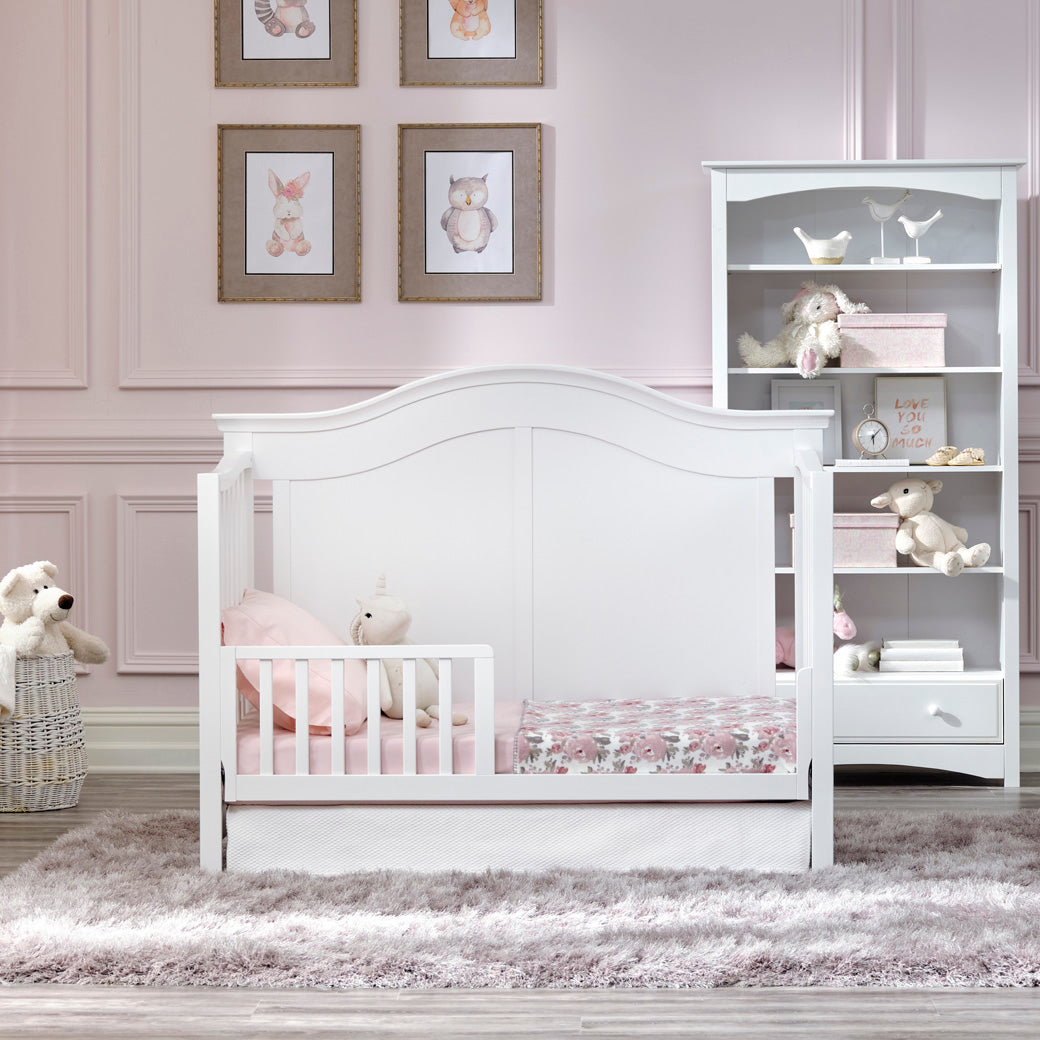 DaVinci Meadow 4-in-1 Convertible Crib as toddler bed next to a bookshelf  in -- Color_White