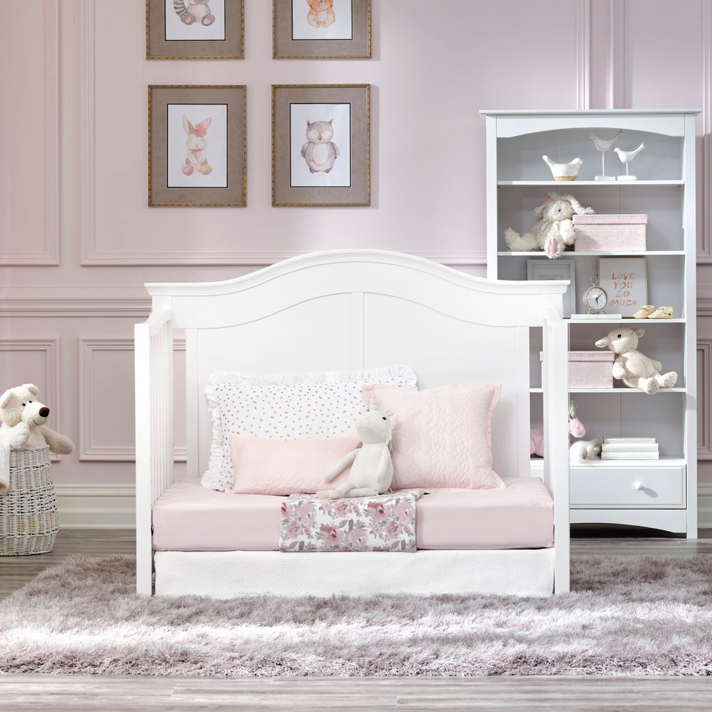 DaVinci Meadow 4-in-1 Convertible Crib as daybed next to a bookshelf  in -- Color_White