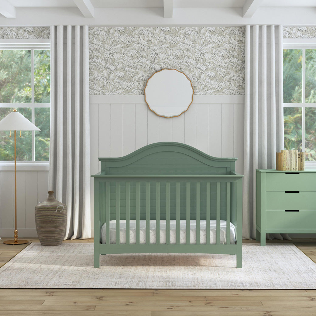 Front view of Carter's by DaVinci Nolan 4-in-1 Convertible Crib next to a dresser  in -- Color_Light Sage