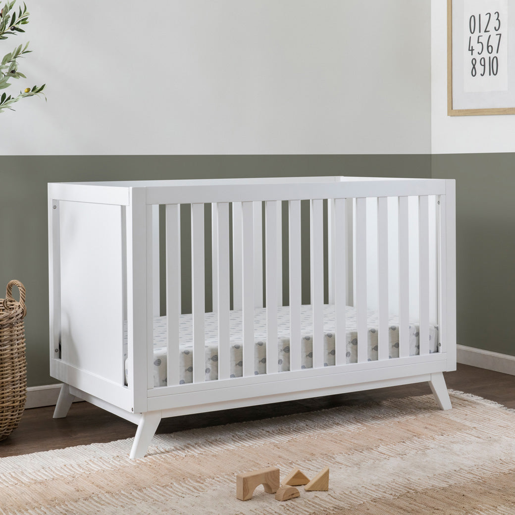 DaVinci Otto 3-in-1 Convertible Crib next to a basket in -- Color_White _ Wood