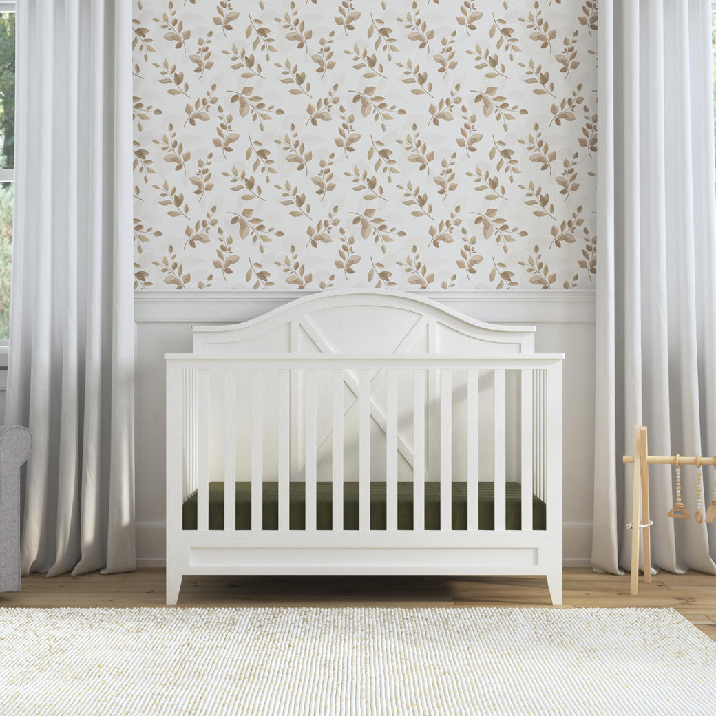 Front view of DaVinci Sawyer Farmhouse 4-in-1 Convertible Crib next to curtains  in -- Color_Heirloom White
