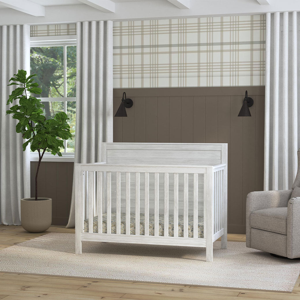 DaVinci Fairway 4-in-1 Convertible Crib next to a recliner and window in -- Color_Cottage White