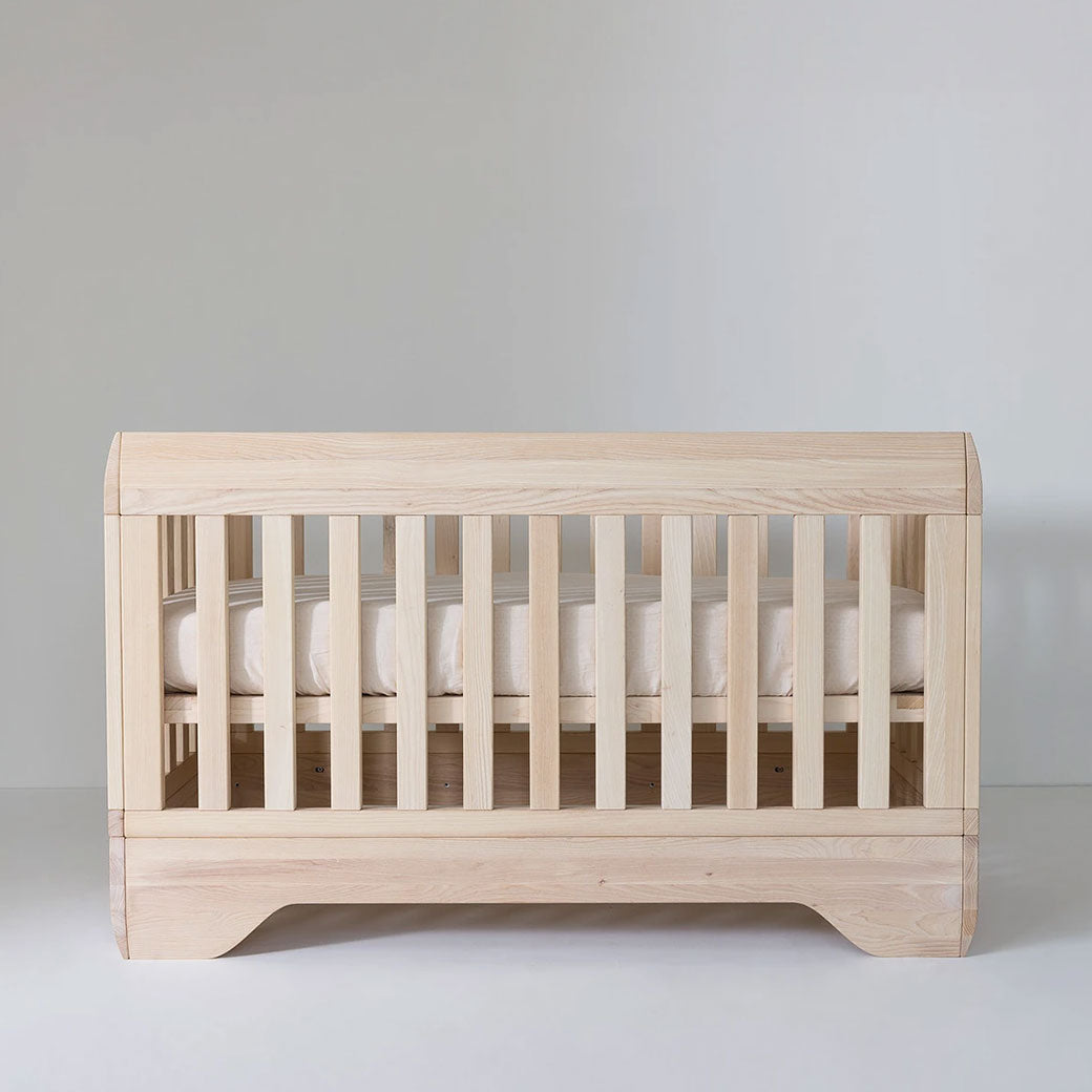Front view of Kalon Echo Crib with mattress positioned in the middle  in -- Color_Ash