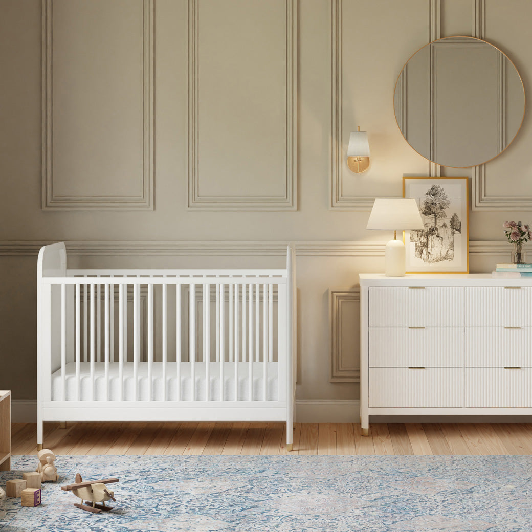 Front view of Namesake Brimsley 3-in-1 Convertible Crib next to a dresser in -- Color_Warm White