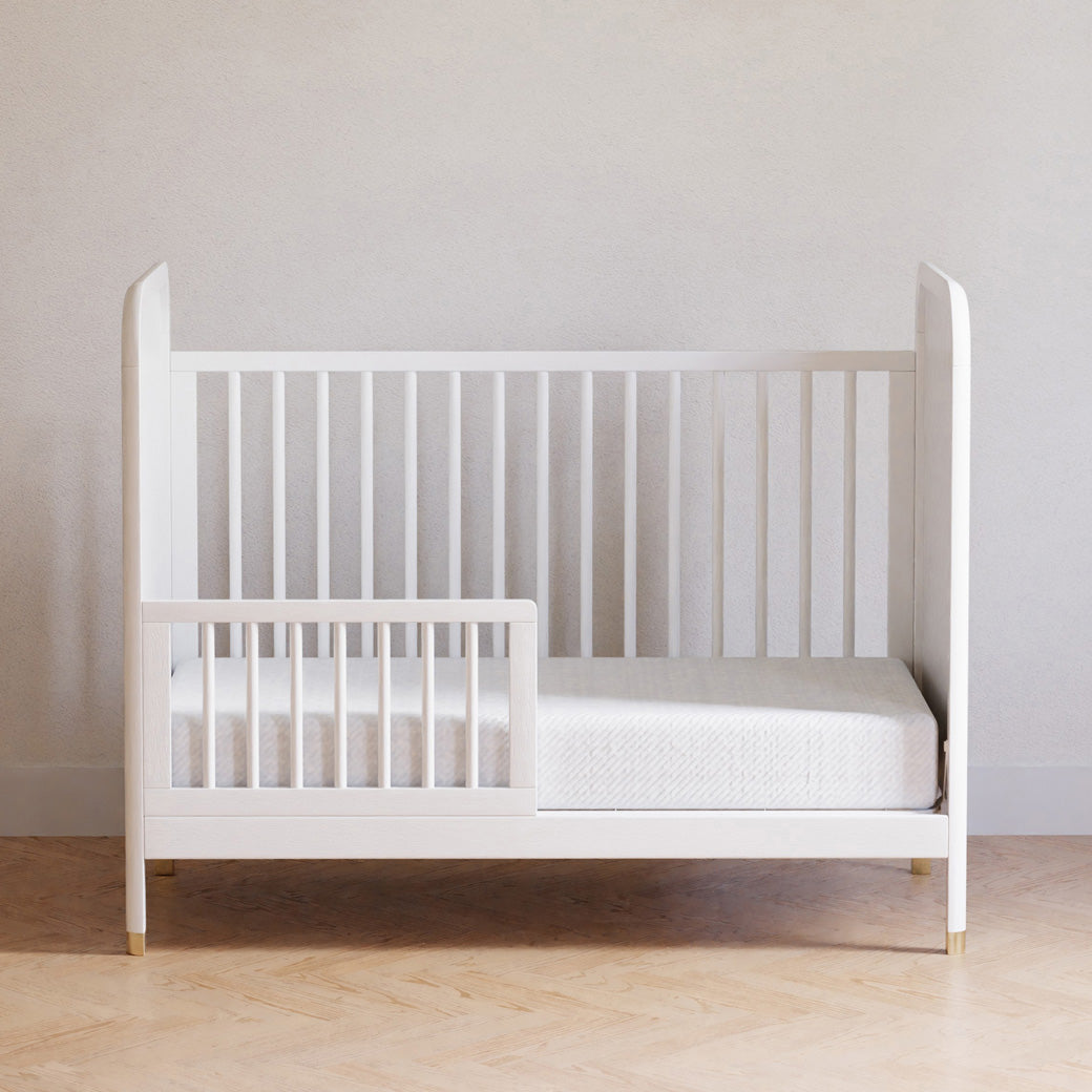 Front view of Namesake Brimsley 3-in-1 Convertible Crib as a toddler bed in a white-wall room  in -- Color_Warm White