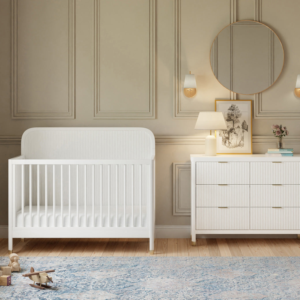 Front view of Namesake Brimsley 4-in-1 Convertible Crib next to a dresser in -- Color_Warm White