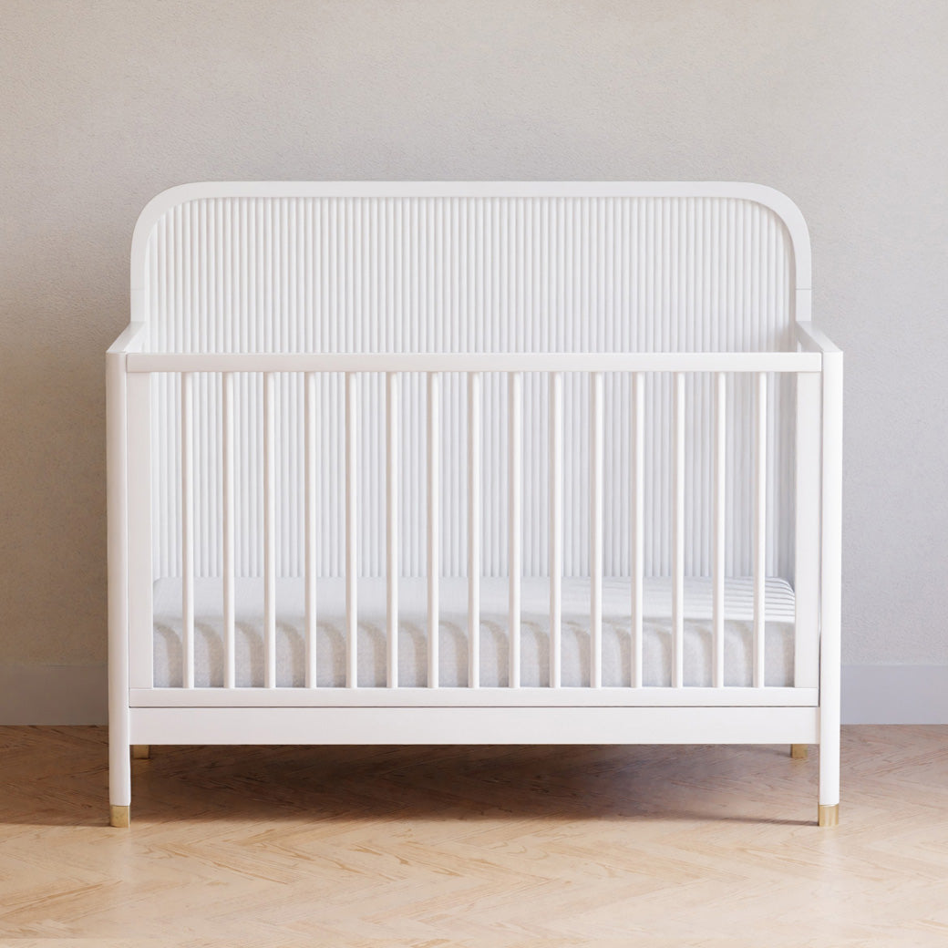 Front view of Namesake Brimsley 4-in-1 Convertible Crib in a white-wall room in -- Color_Warm White