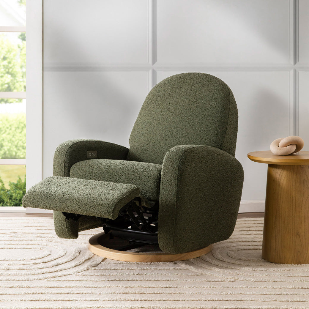 The Babyletto Nami Glider Recliner with footrest up next to a coffee table in -- Color_Olive Boucle with Light Wood Base