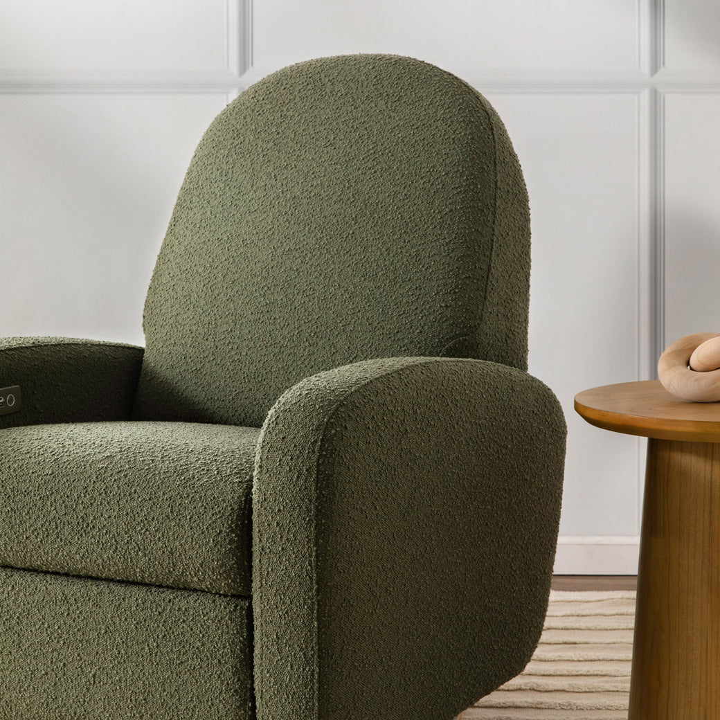 The Babyletto Nami Glider Recliner in a room next to a table  in -- Color_Olive Boucle with Light Wood Base