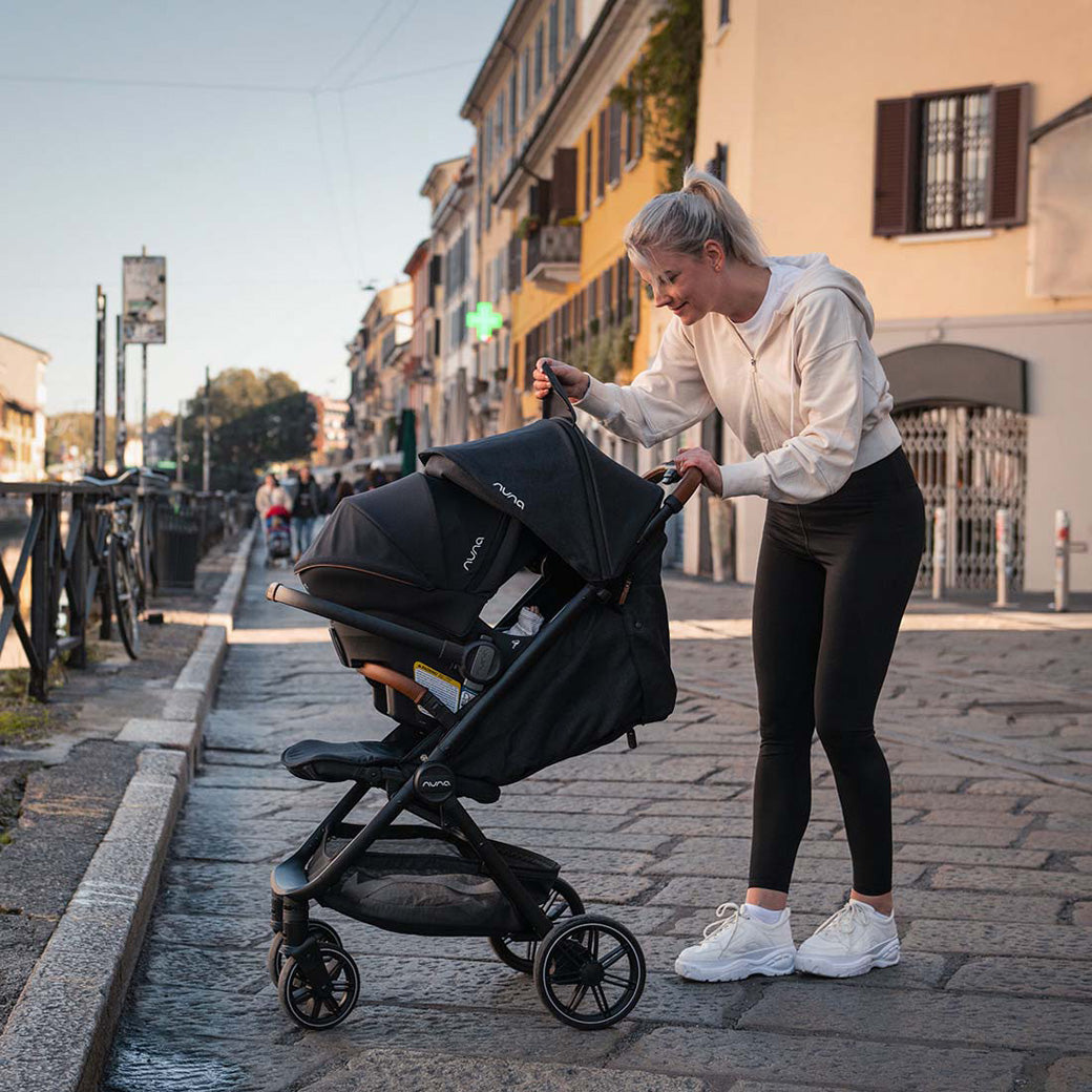 Mom pushing baby in the Nuna TRVL lx Stroller + PIPA Urbn Travel System in -- Color_Caviar