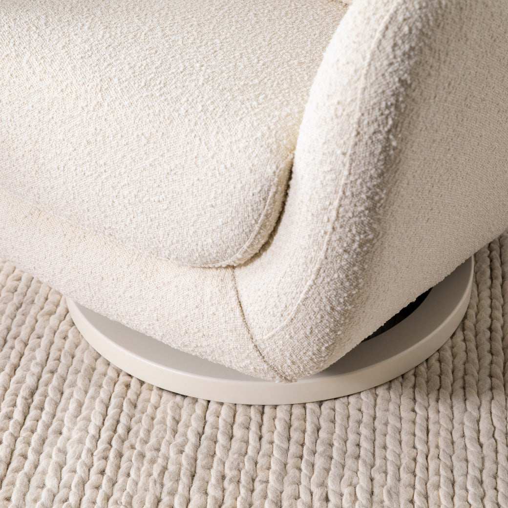 Closeup of The Nursery Works Solstice Swivel Glider base in --Color_Ivory Boucle with Ivory Wood Base