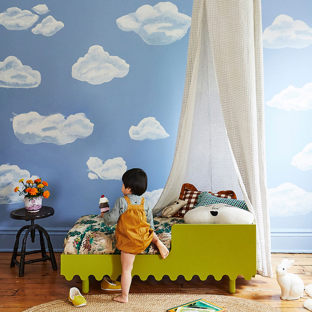 Toddler climbing on the Oeuf Moss Toddler Bed in -- Color_Peapod
