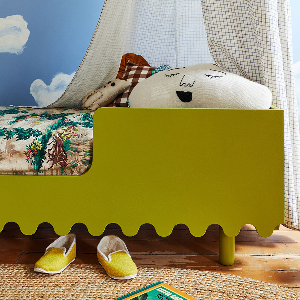 Closeup of Oeuf Moss Toddler Bed with slippers underneath in -- Color_Peapod