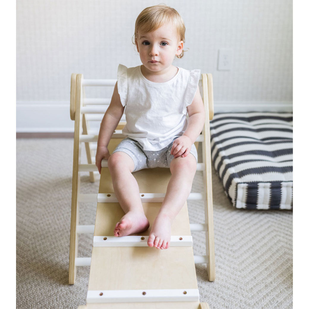 Baby sitting on the Poppyseed Play Climbing Triangle & Ramp in -- Color_White