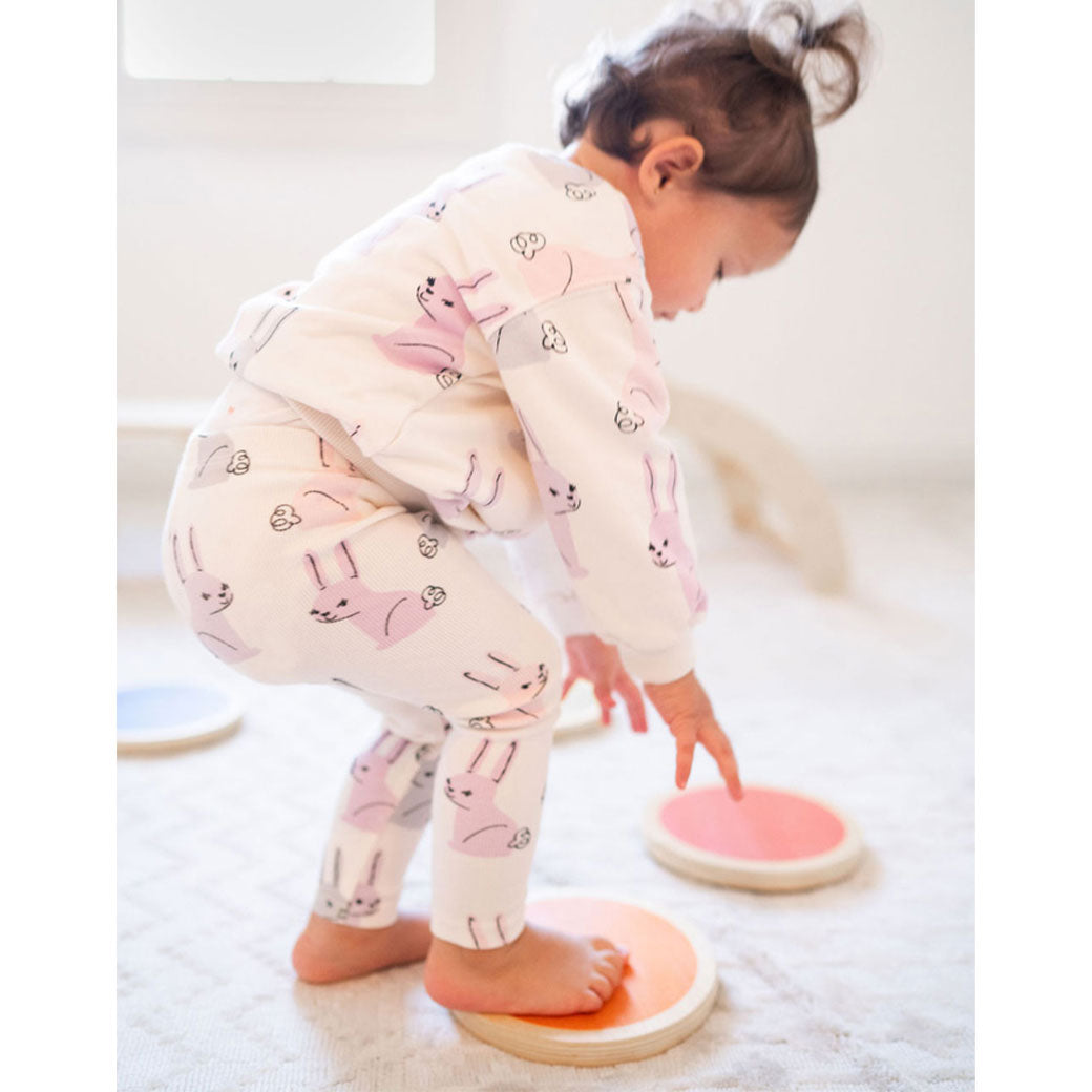Toddler in bunny pajamas playing with the Poppyseed Play Stepping Stones