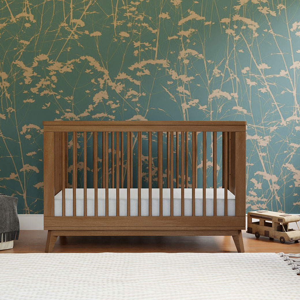 Front view of Babyletto's Scoot 3-in-1 Convertible Crib in a room in -- Color_Natural Walnut