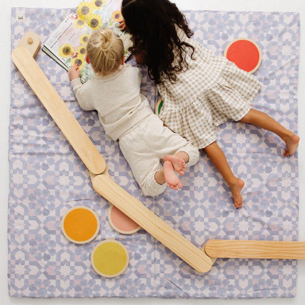 Two kids reading a book on the Toki Mats Padded Organic Cotton Play Mat in -- Color_Blue Tile