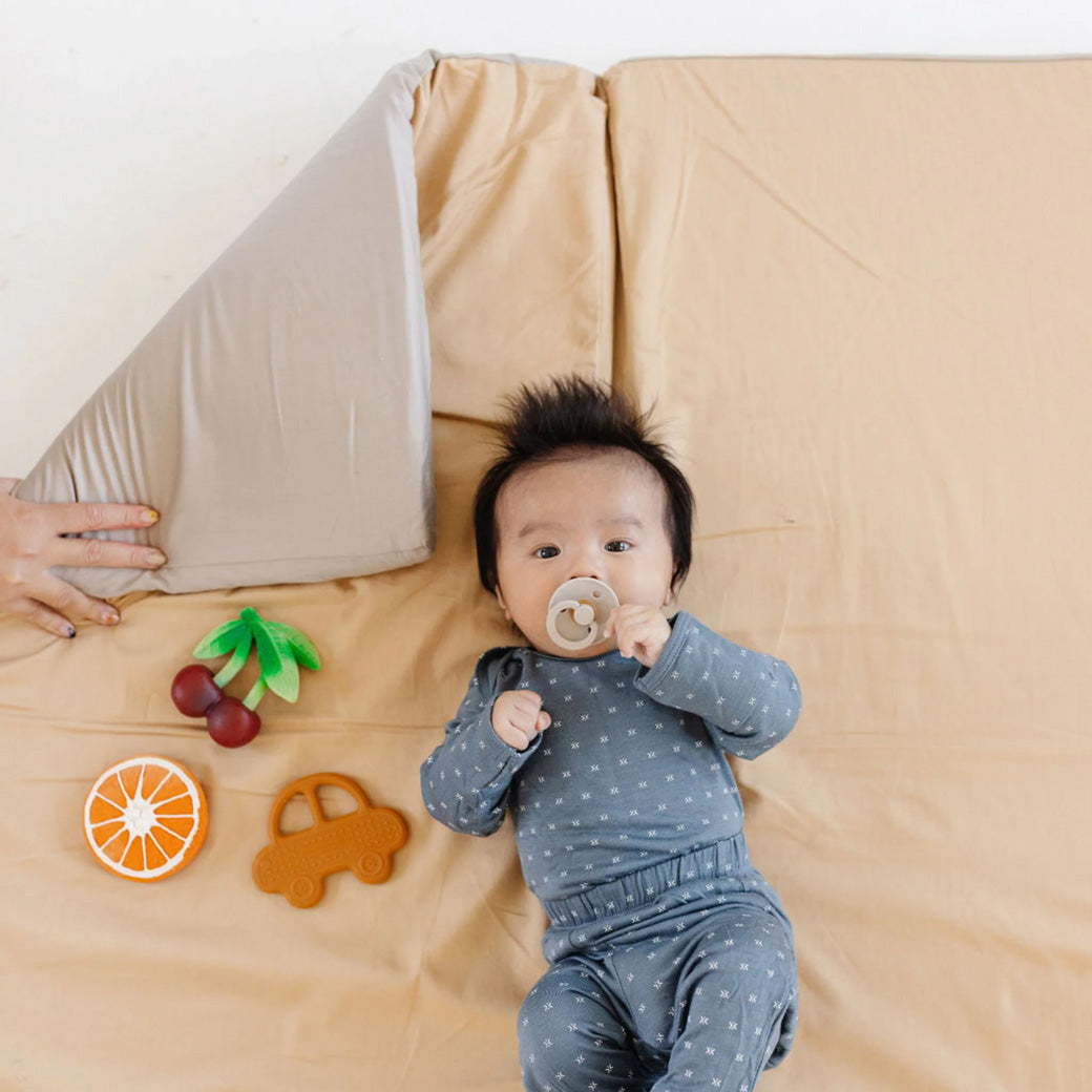Baby laying on the Toki Mats Padded Organic Cotton Play Mat in -- Color_Cloud + Sandcastle