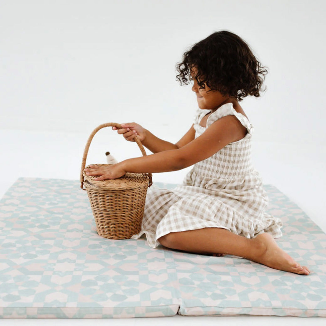 Toddler with a basket on the Toki Mats Padded Organic Cotton Play Mat in -- Color_Green Tile