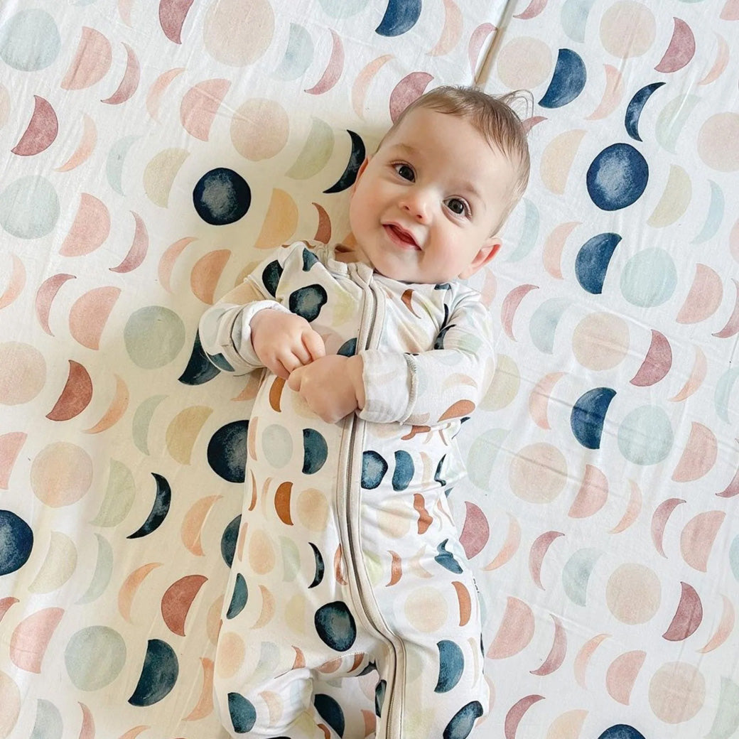 Baby laying on the Toki Mats Padded Organic Cotton Play Mat in -- Color_Lunar Phases
