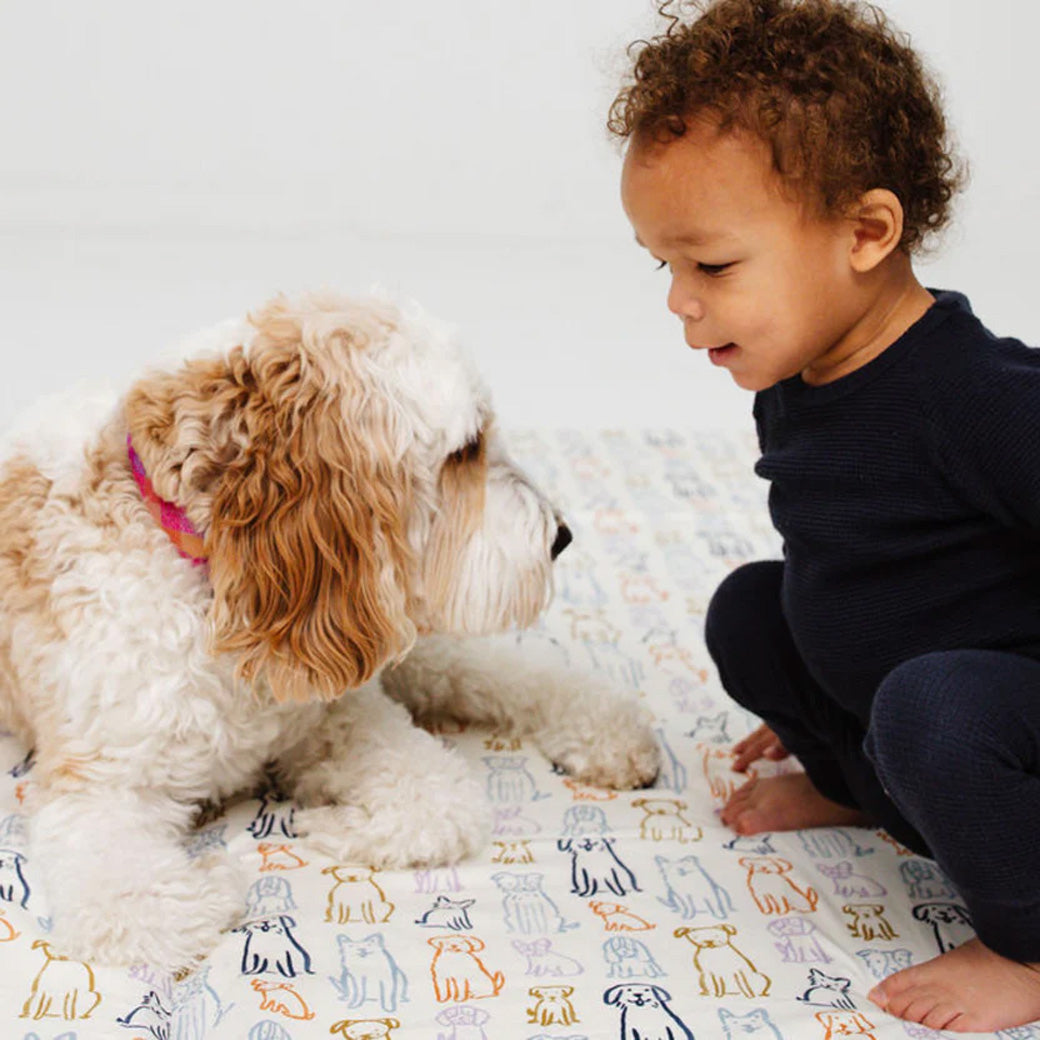 Child and a puppy sitting on the Toki Mats Padded Organic Cotton Play Mat in -- Color_Dogs