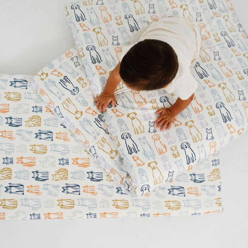 A baby crawling on the Toki Mats Padded Organic Cotton Play Mat in -- Color_Dogs