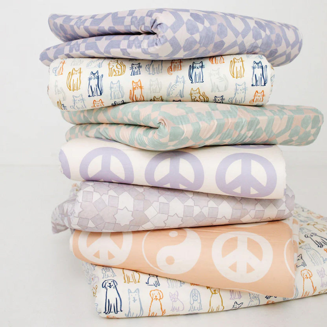 The Toki Mats Padded Organic Cotton Play Mat folded in a pile of mats in -- Color_Dogs