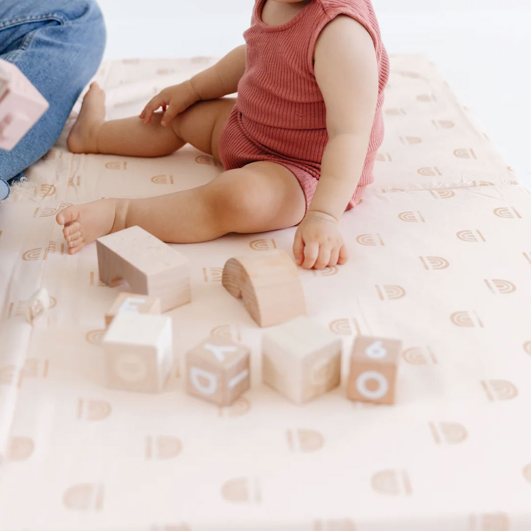 Baby with blocks on the Toki Mats Padded Organic Cotton Play Mat in -- Color_Rainbow Cream