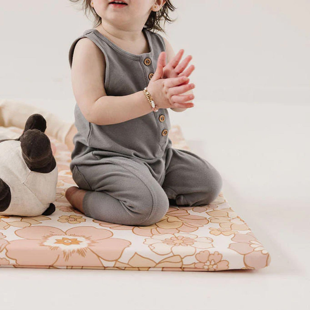Baby sitting on the Toki Mats Vegan Leather Play Mat with toy  in -- Color_Blooms 