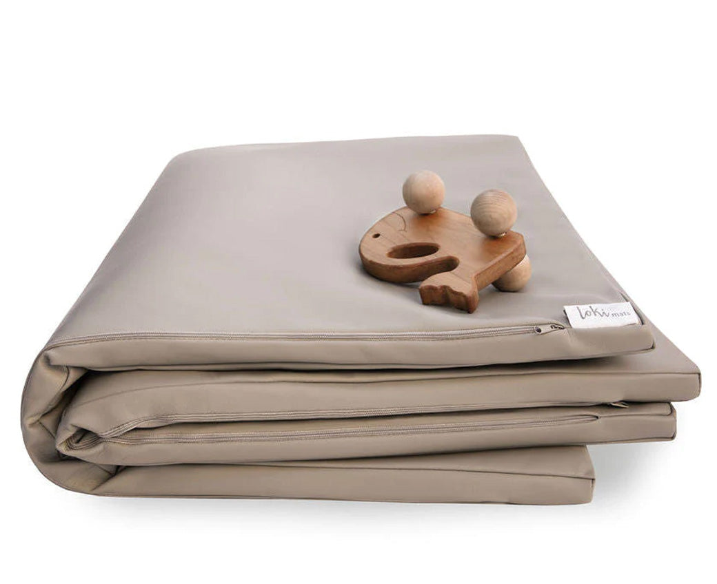 A toy on top of the folded Toki Mats Vegan Leather Play Mat in -- Color_Pebble