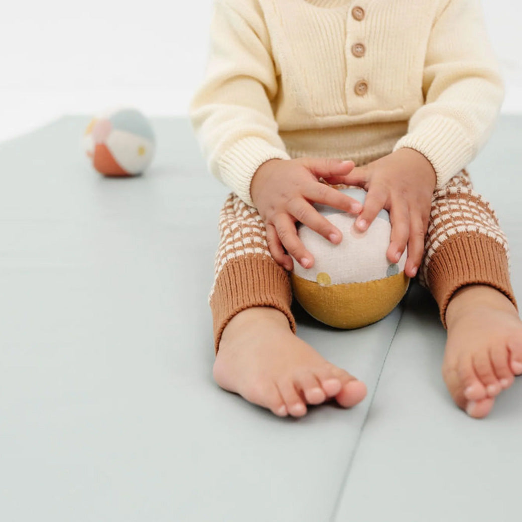 Baby with a ball playing on the Toki Mats Vegan Leather Play Mat in -- Color_Sage