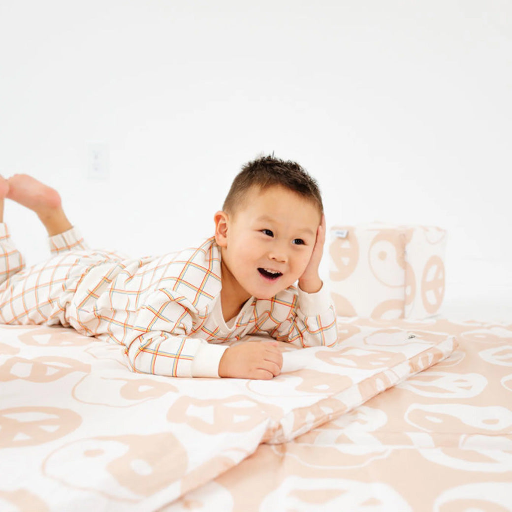 Toddler laying and smiling on the Toki Mats Padded Organic Cotton Play Mat in -- Color_Yin Yang