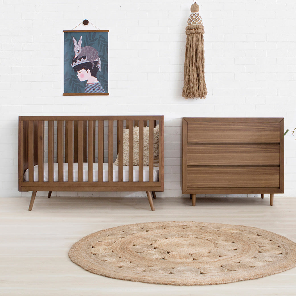 Ubabub Nifty Timber 3-In-1 Crib next to a dresser in -- Color_Walnut