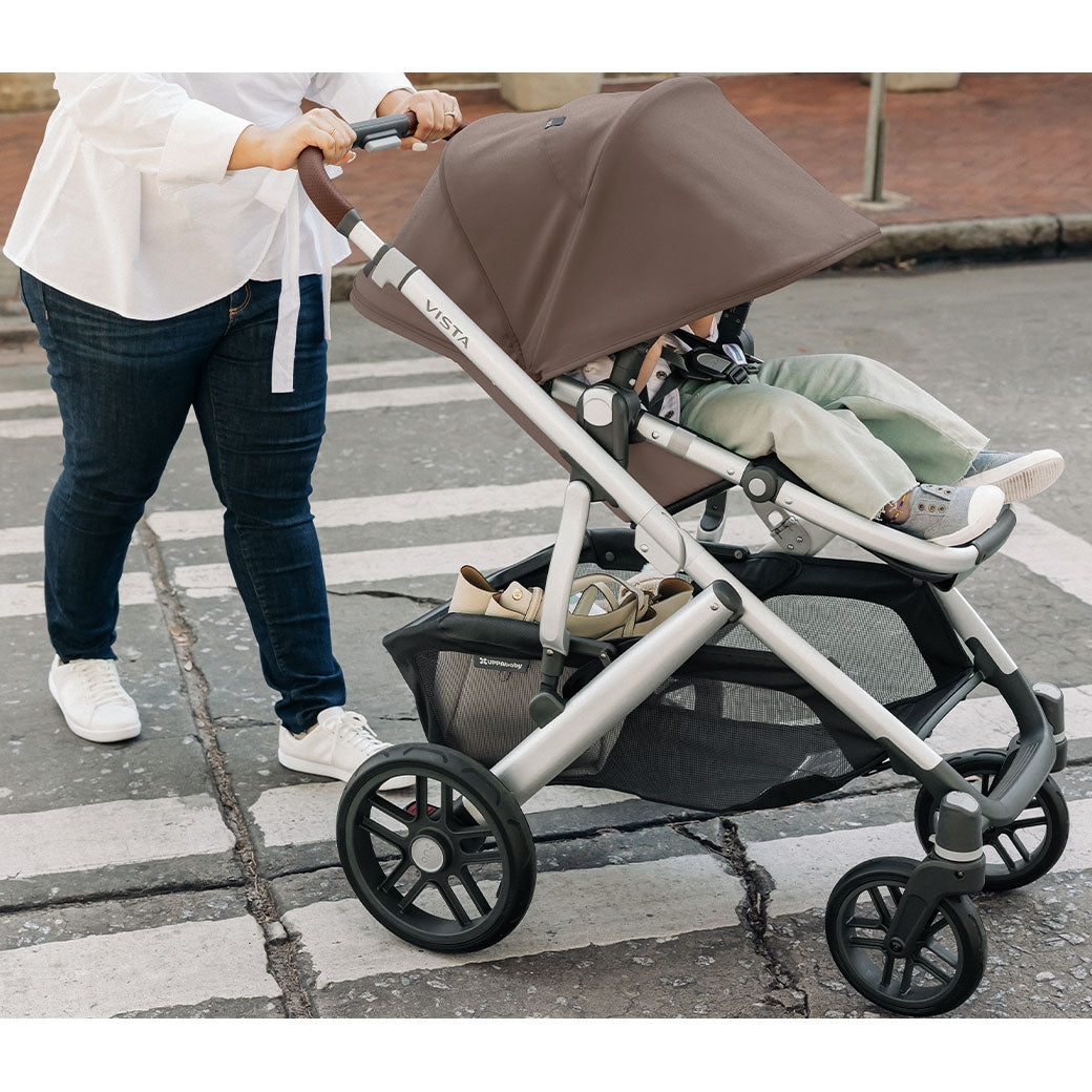 Mom pushing baby across the street in the UPPAbaby VISTA V2 Travel System stroller in -- Color_Theo