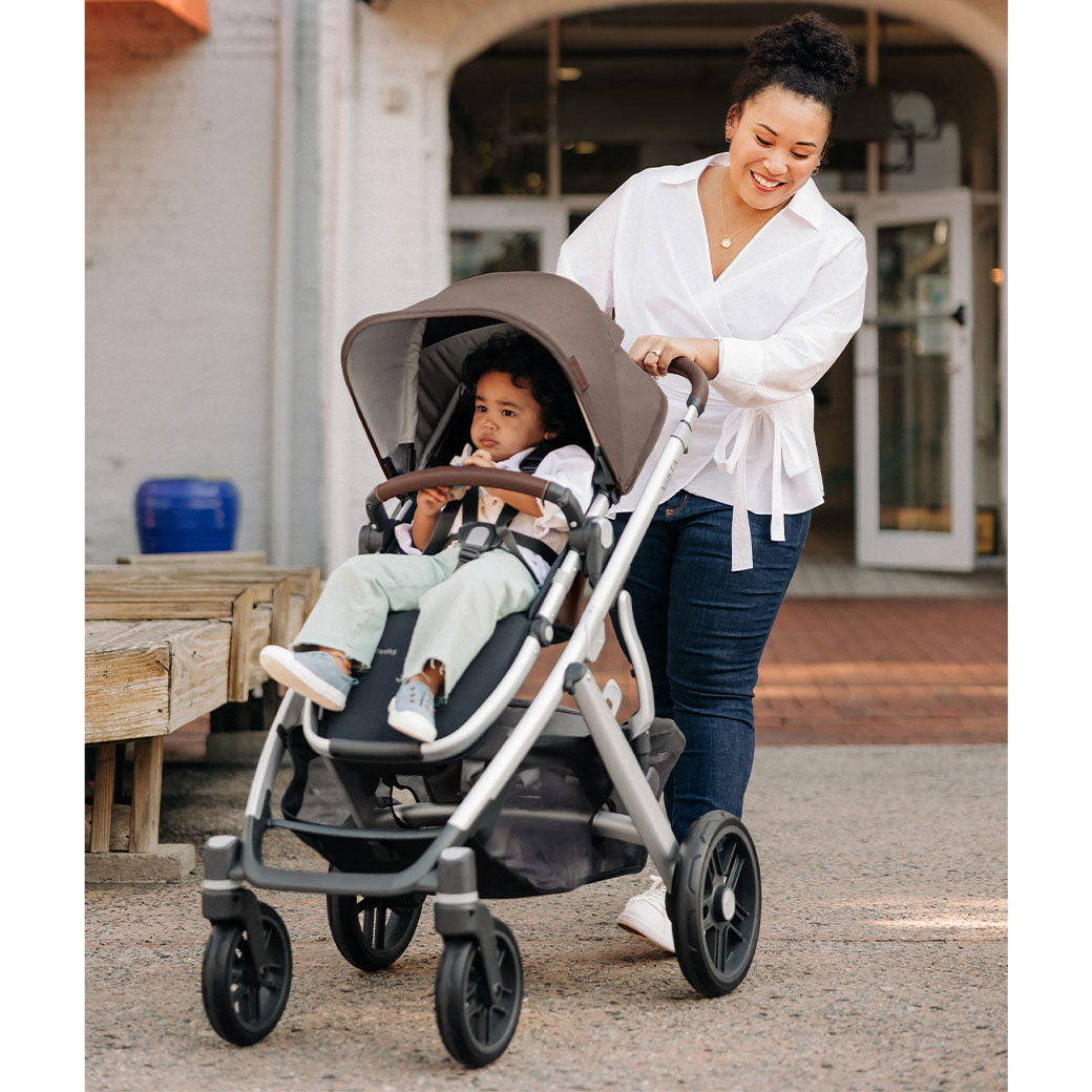 A mom smiling as she is pushing her baby in the Uppababy Vista V2 in -- Color_Theo