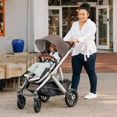 Mom pushing baby in the UPPAbaby VISTA V2 Travel System stroller in -- Color_Theo
