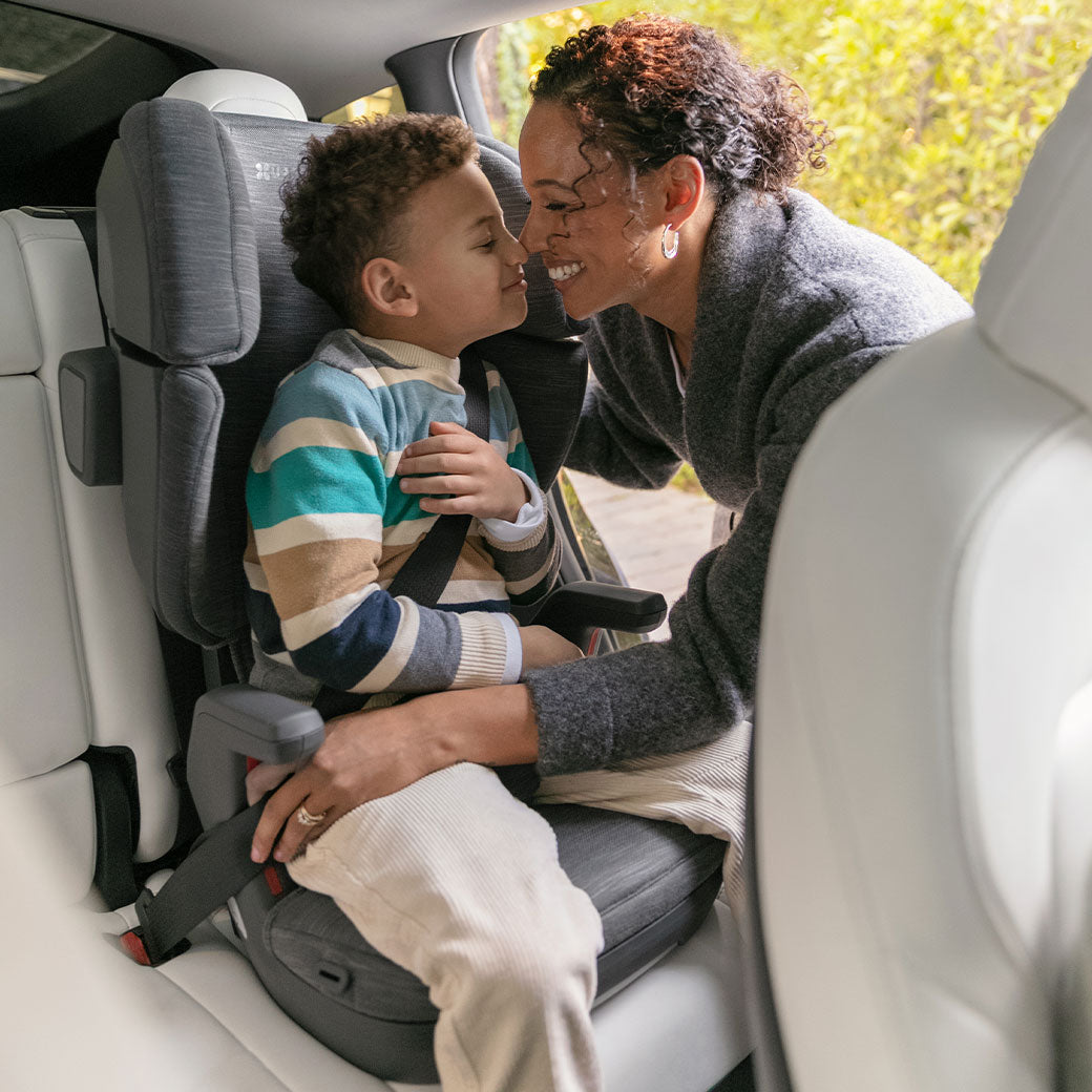 Mom smiling with child sitting in the Uppababy Alta V2 Booster Seat in -- Lifestyle
