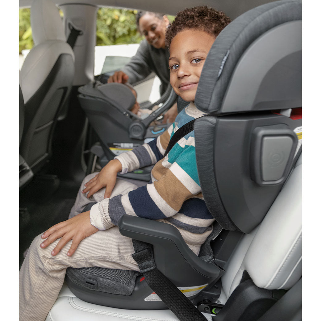 Child sitting in the Uppababy Alta V2 Booster Seat and smiling  in -- Lifestyle