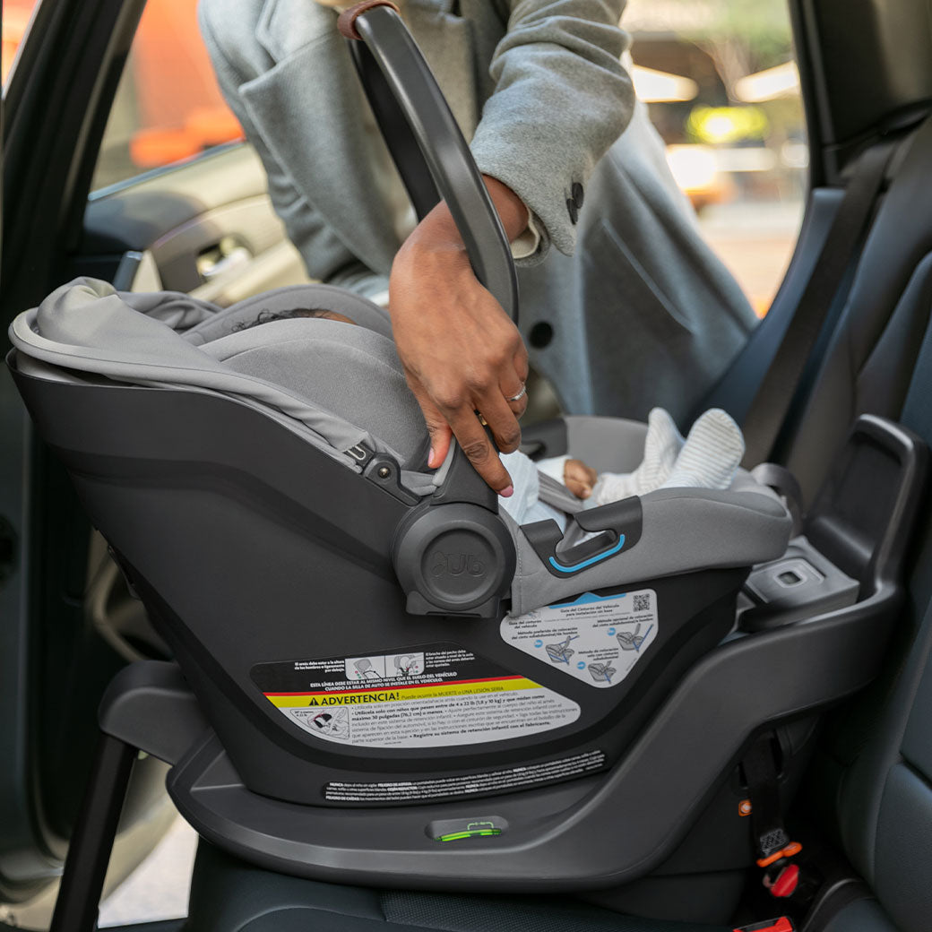Mom putting baby in car in the Uppababy Aria Infant Car Seat in -- Color_Anthony