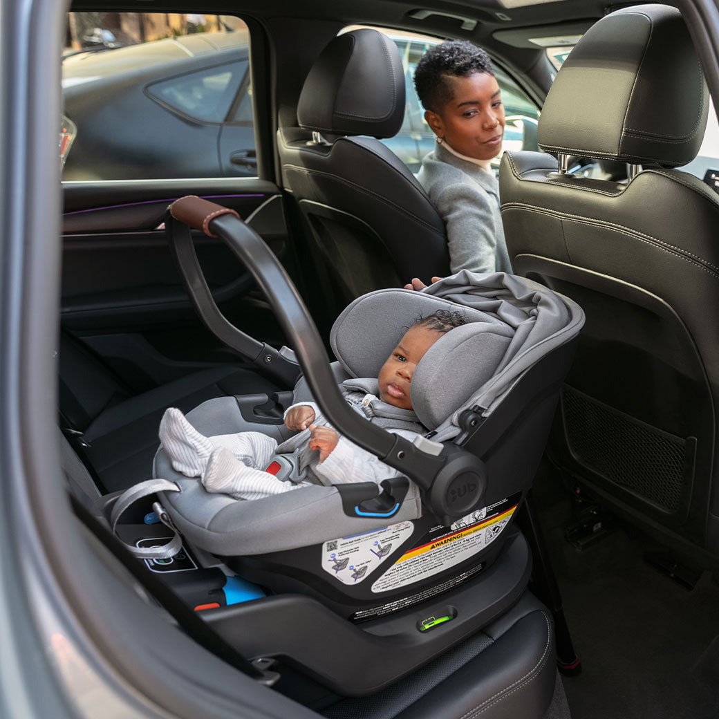 Mom checking baby sitting in the back seat in the Uppababy Aria Infant Car Seat in -- Color_Anthony
