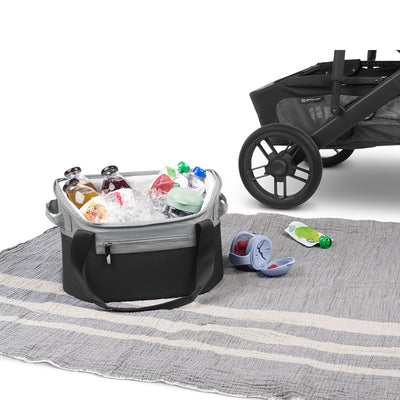 Open UPPAbaby Bevvy Stroller Basket Cooler on a picnic blanket next to a stroller, food, and beverages