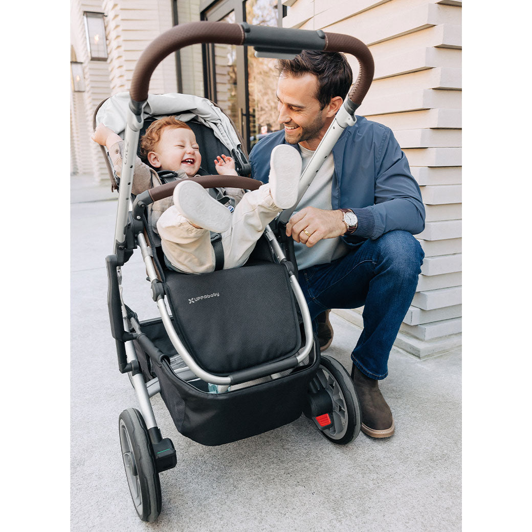 A dad and a happy baby in the UPPAbaby Cruz V2 Stroller in -- Color_Theo