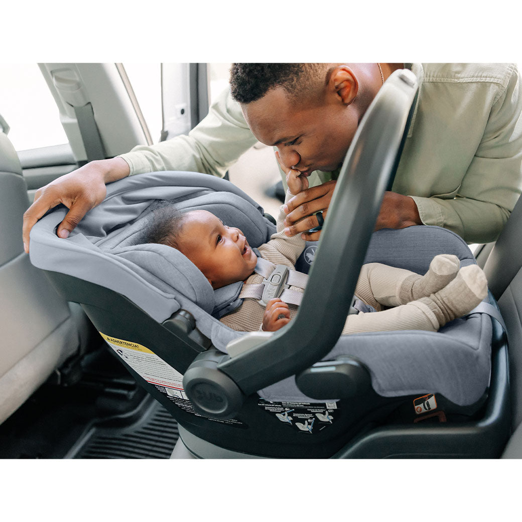 Baby in the UPPAbaby MESA V2 Infant Car Seat smiling at dad in -- Color_Gregory