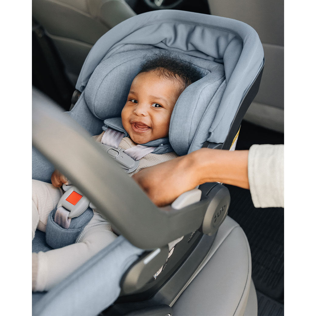 Baby in the back seat of a car in the UPPAbaby MESA V2 Infant Car Seat in -- Color_Gregory