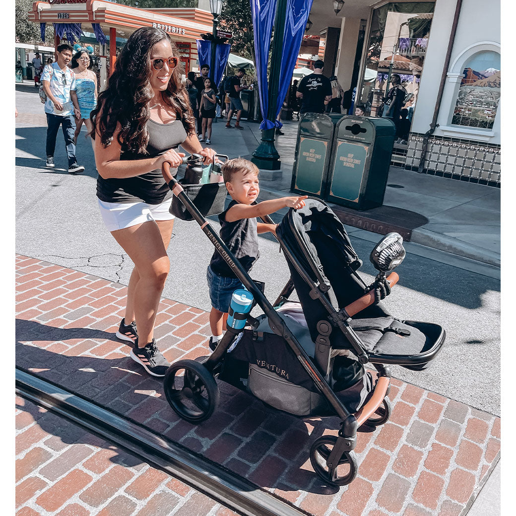 Mom walking with a toddler standing on the Venice Child Ventura Single to Double Sit-and-Stand Stroller in -- Lifestyle