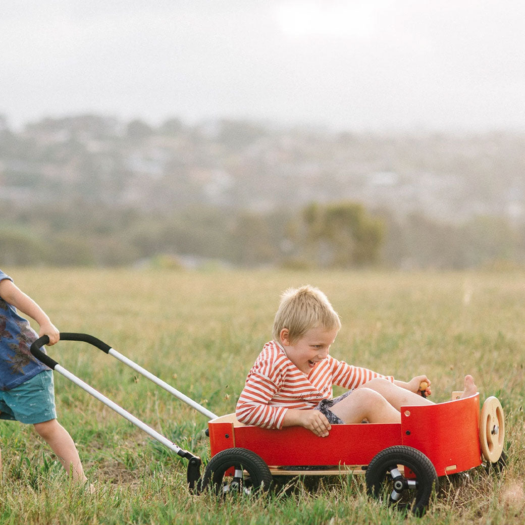 One child pulling another in the Wishbone Wagon in Red