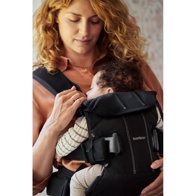 Mom looking down at the baby in BABYBJÖRN Baby Carrier One in -- Color_Black Cotton