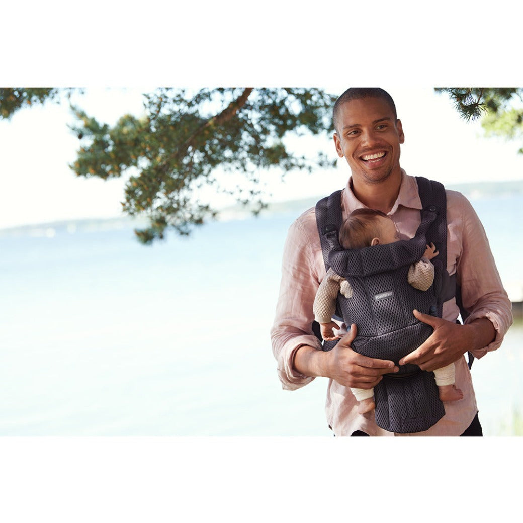 Dad laughing by the lake with the baby in the BABYBJÖRN Baby Carrier Free in -- Color_Anthracite 3D Mesh