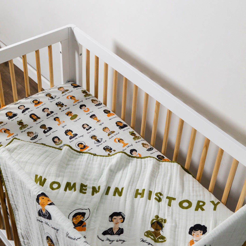 A crib with blanket equipped with the Babyletto's Crib Sheet in GOTS Certified Organic Muslin Cotton in --Color_Women In History