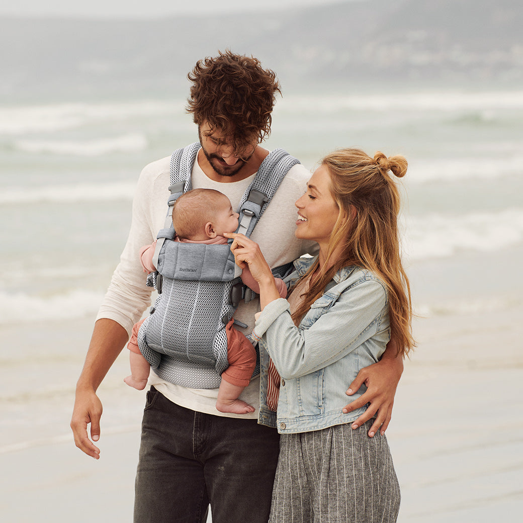 Dad holding baby in Babybjorn Baby Carrier Harmony with mom next to them in -- Color_Silver